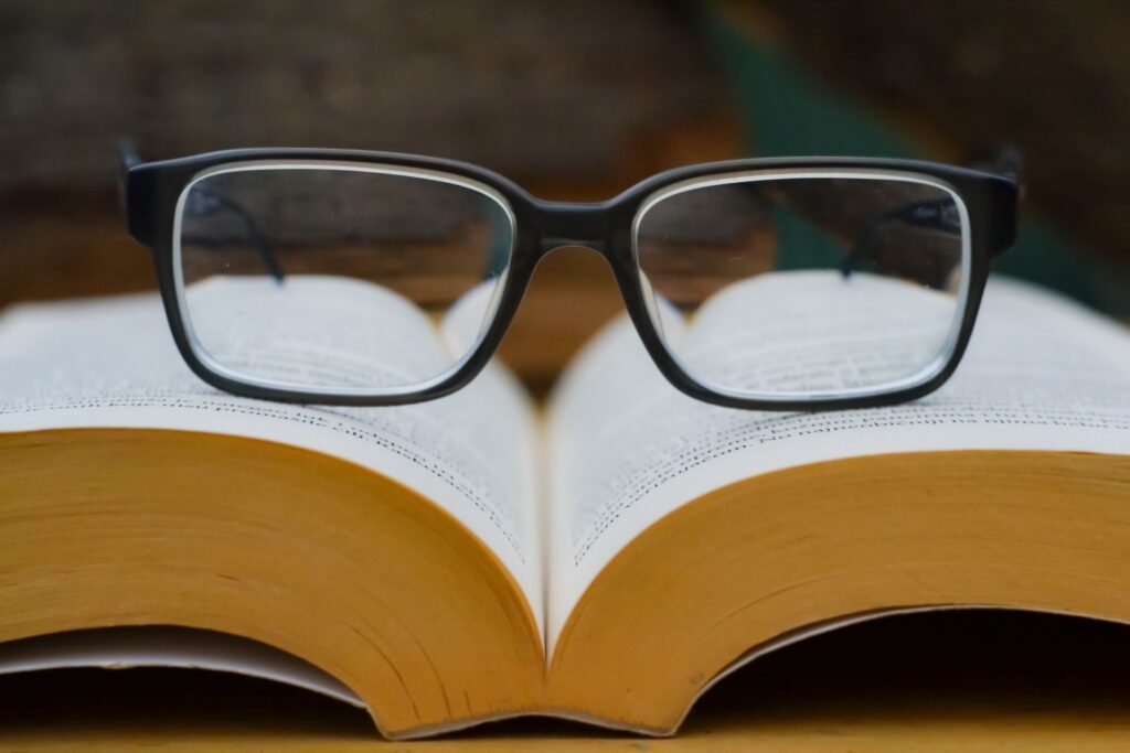 Eyeglasses resting on an open book, highlighting reading and education theme.